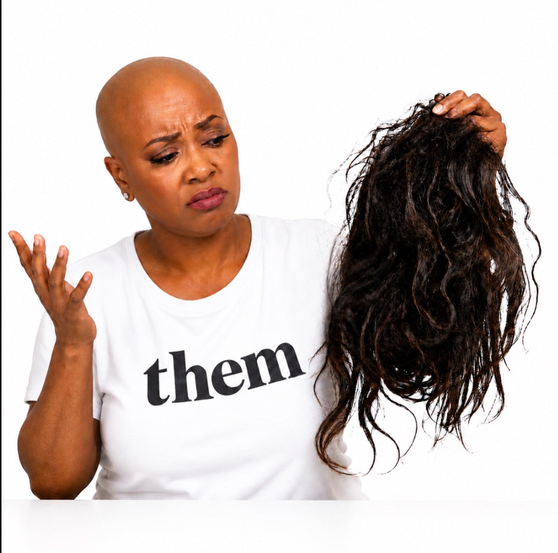 Person wearing a white shirt with 'them' text, holding a bundle of hair extensions.